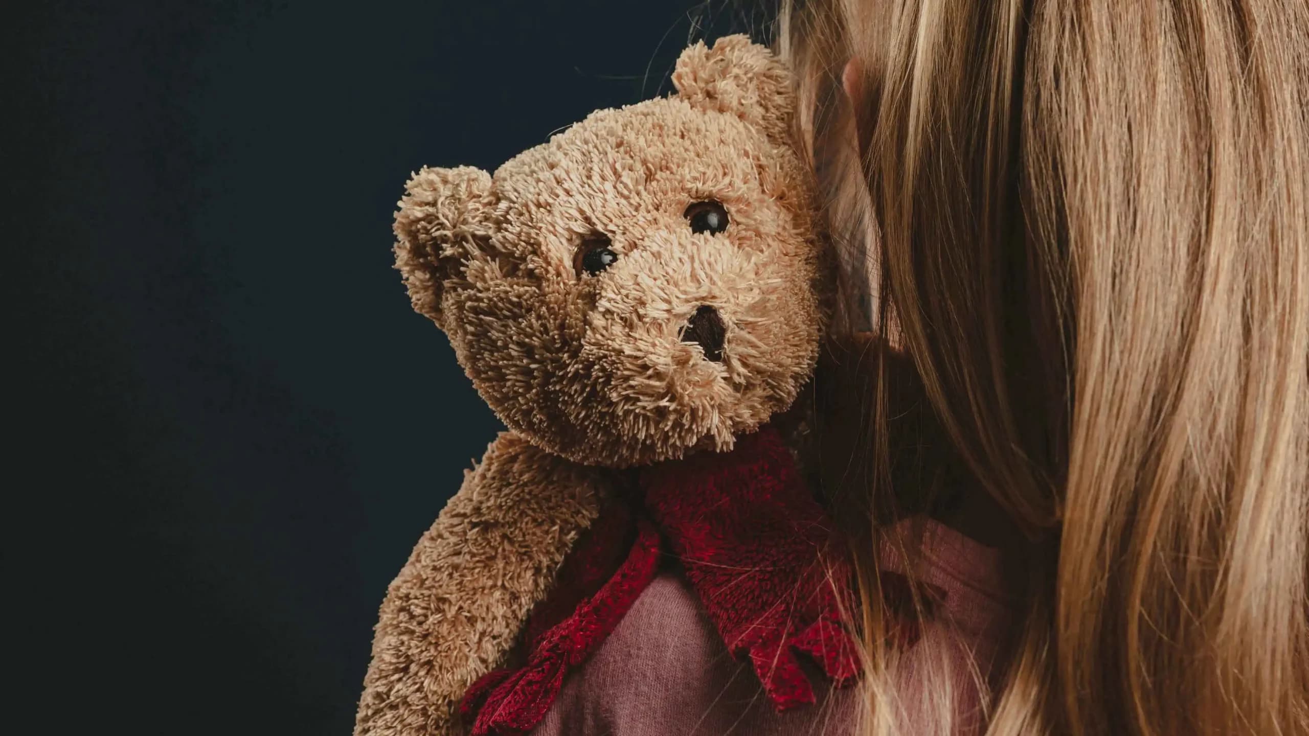 niña abrazando oso de peluche