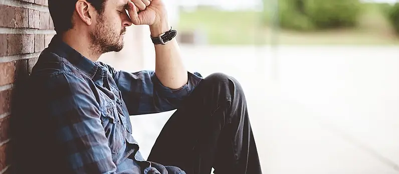 lonely depressed person sitting near brick wall