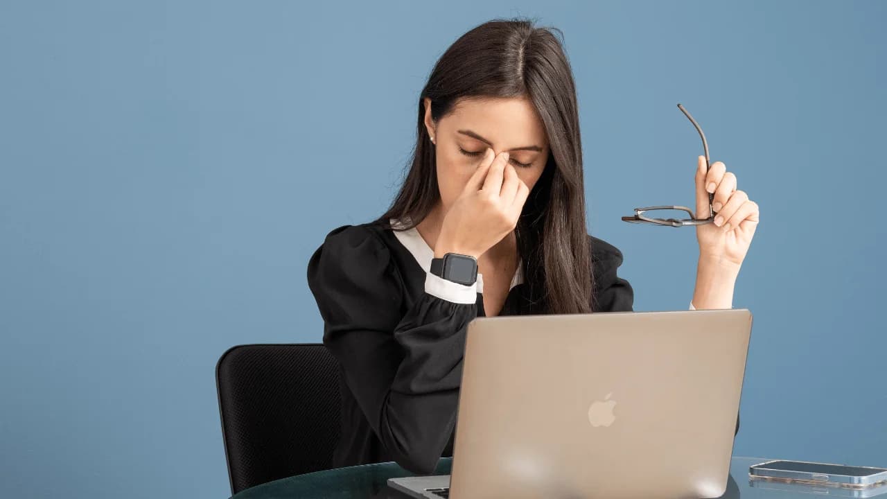 mujer con stress tocandose la frente y mirando el computador