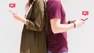 Imagen de un hombre y una mujer de espaldas con el celular en la mano enviando likes 